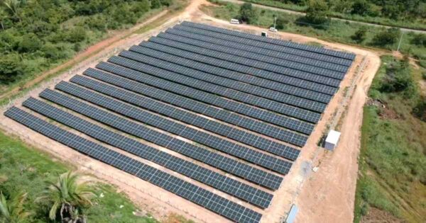Vista aérea de usina fotovoltaica com múltiplas fileiras de painéis solares instalados em terreno aberto, representando projeto de geração distribuída no Brasil.